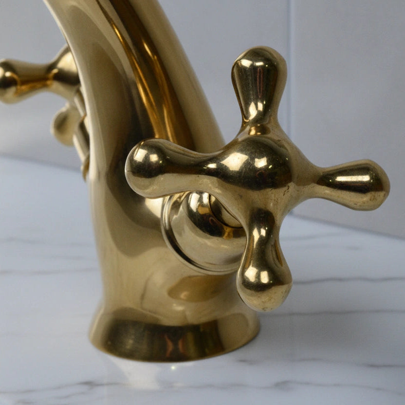 Gold faucet on a marble countertop with a white background