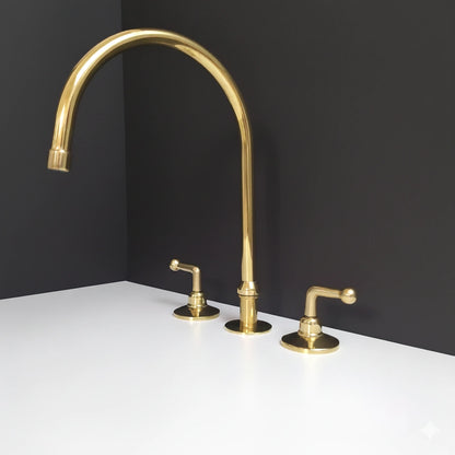 Gold kitchen faucet set on a white countertop with a black wall background