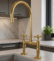 Gold kitchen faucet in a modern kitchen setting with marble countertop and cabinets.