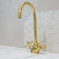 Gold faucet on a marble countertop with a light gray wall background