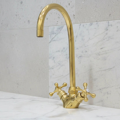 Gold faucet on a marble countertop with a light gray wall background