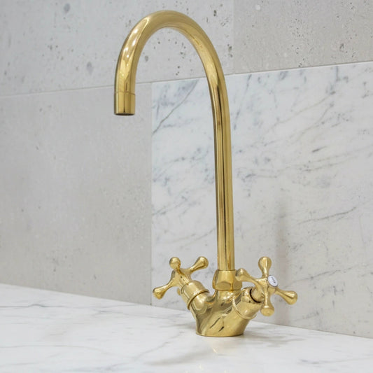 Gold faucet on a marble countertop with a light gray wall background