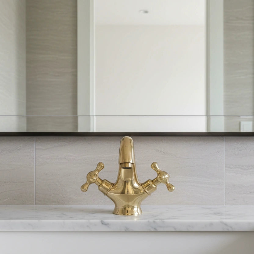 Gold faucet on a marble sink with a mirror above in a bathroom setting