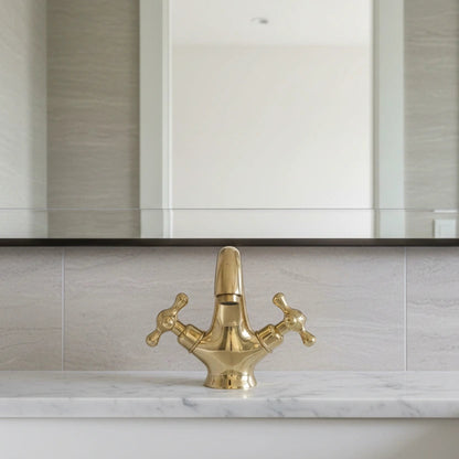 Gold faucet on a marble sink with a mirror above in a bathroom setting