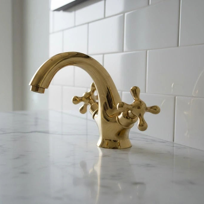 Gold faucet on a white tiled wall